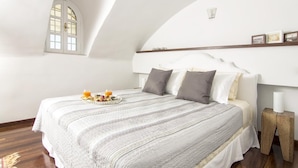 Un dormitorio con una cama grande, una ventana pequeña y una mesita de noche de madera.