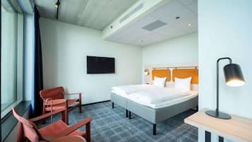 Ein Hotelzimmer mit Bett, Schreibtisch, Stuhl, Fernseher und Fenster.