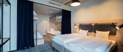 A hotel room with a large bed, a desk, and a wardrobe.
