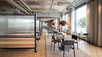 Un espacio de oficina moderno con una amplia mesa de conferencias, varias mesas redondas y sillas dispuestas para reuniones.