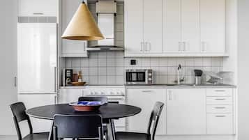 A modern kitchen with white cabinets, a stove, microwave, and a hanging light fixture.
