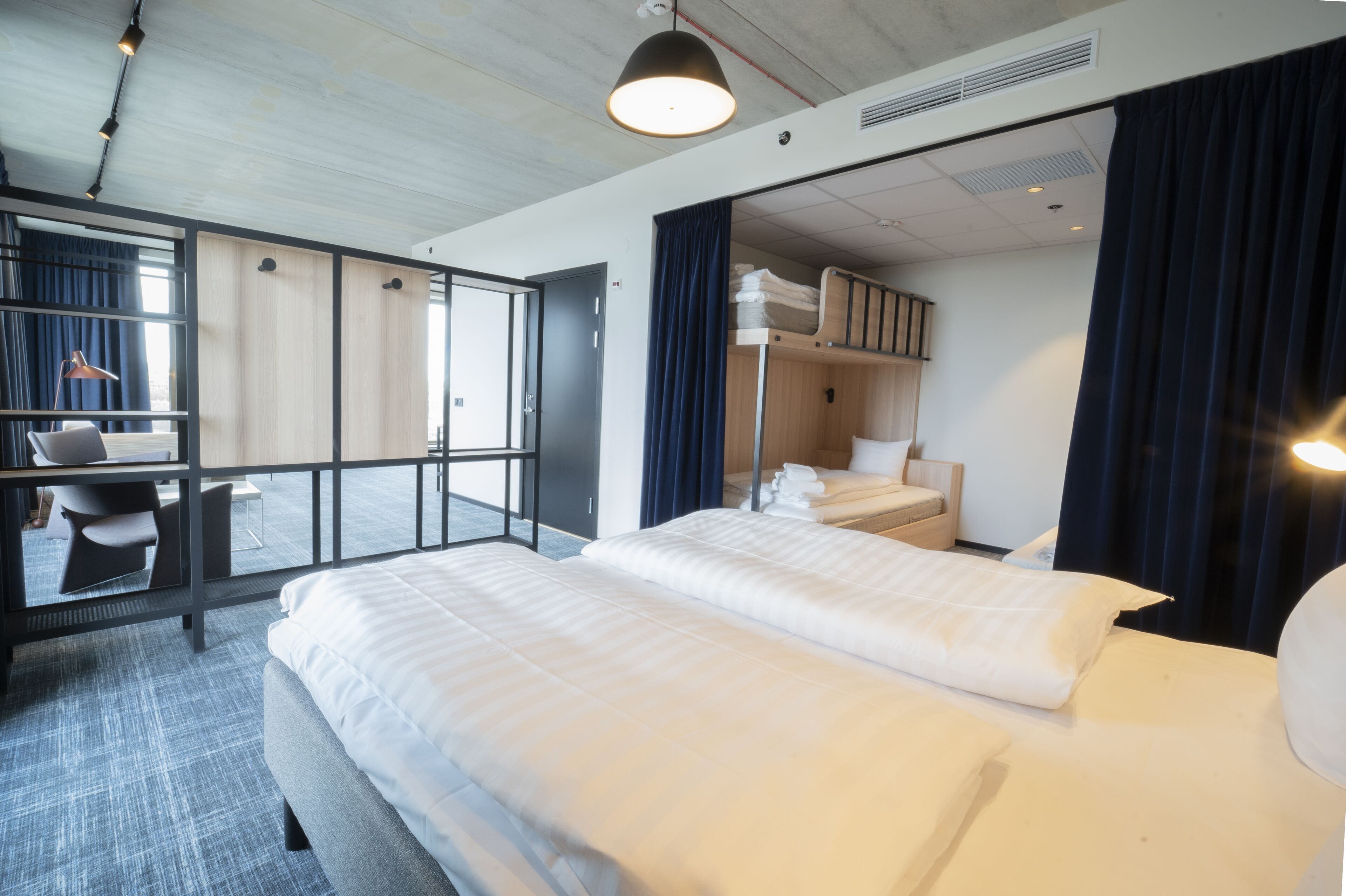 Une chambre d’hôtel moderne équipée de deux lits, d’un bureau et d’une salle de bain.