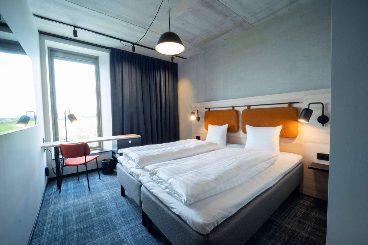 Ett hotellrum med två sängar, ett skrivbord och en stol.