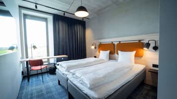 Ett hotellrum med två sängar, ett skrivbord och en stol.