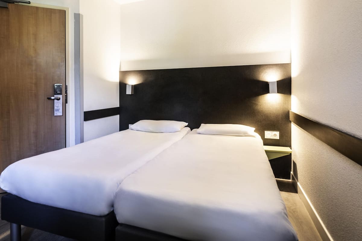 Cama doble con ropa de cama blanca en una habitación de hotel.