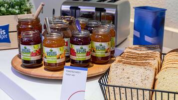 Se exhiben frascos de miel Le Berger Fruits, un tostador y una cesta de pan rebanado.