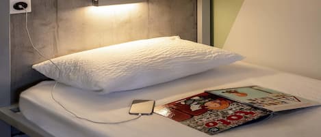 Una cama litera con un cojín y una revista en la cama inferior.