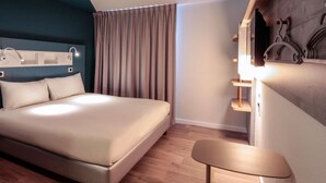 Una habitación de hotel moderna con una cama grande, un escritorio y un espejo.