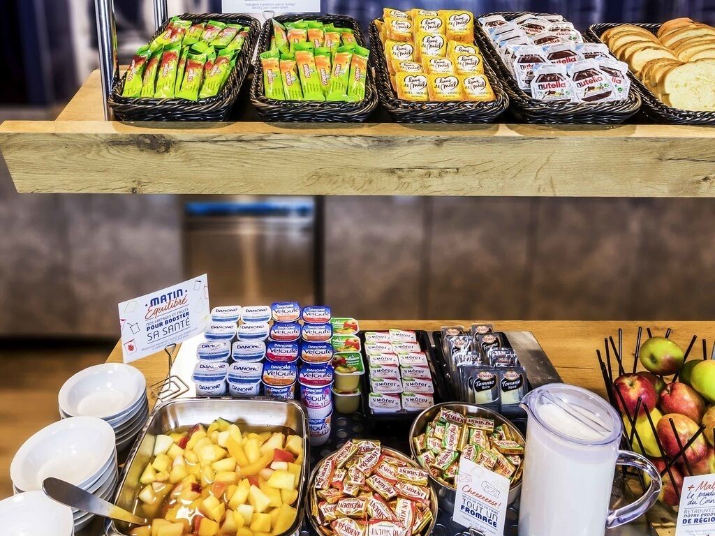 A buffet with various food items including fruits, pastries, and condiments.