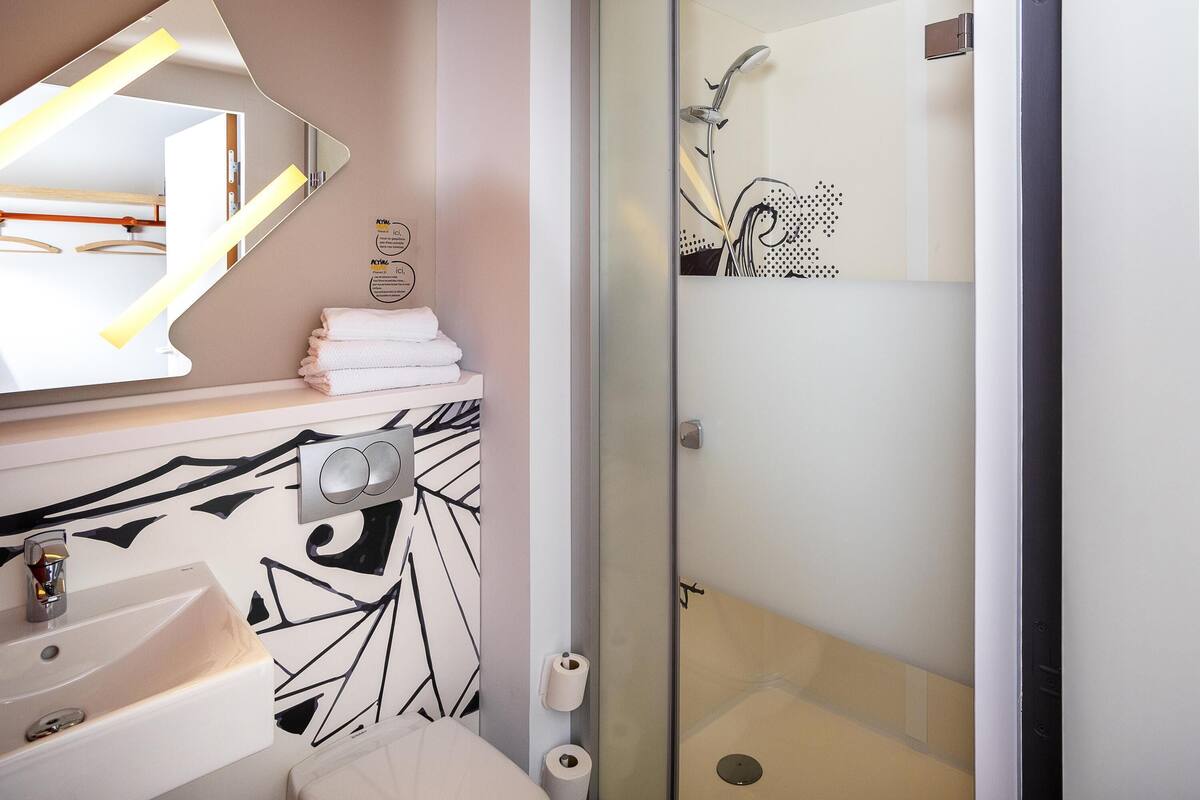 Uma casa de banho moderna com lavatório, espelho e chuveiro.