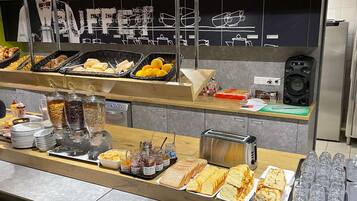 Un mostrador de buffet con diversos alimentos, una máquina de café y un tostador.