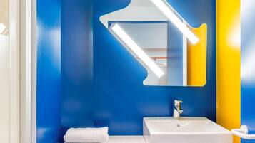 A bathroom with a white sink, a mirror with a unique design, and a towel on the counter.