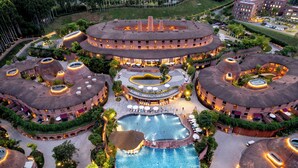 Un hôtel doté d’une piscine centrale, de plusieurs bâtiments de forme circulaire et d’espaces de détente en plein air.
