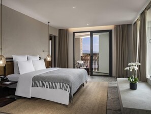 Ein modernes Hotelzimmer mit einem großen Bett, einem Schreibtisch, einem Balkon mit Blick und einer Topfpflanze.