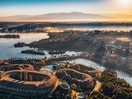 Un gran complejo de edificios circulares con varias estructuras abovedadas, rodeado de agua y árboles.