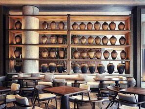 Ein Restaurantinneres mit mehreren Holzböden, die Vasen zeigen, gepolsterten Sitzgelegenheiten und Tischen.