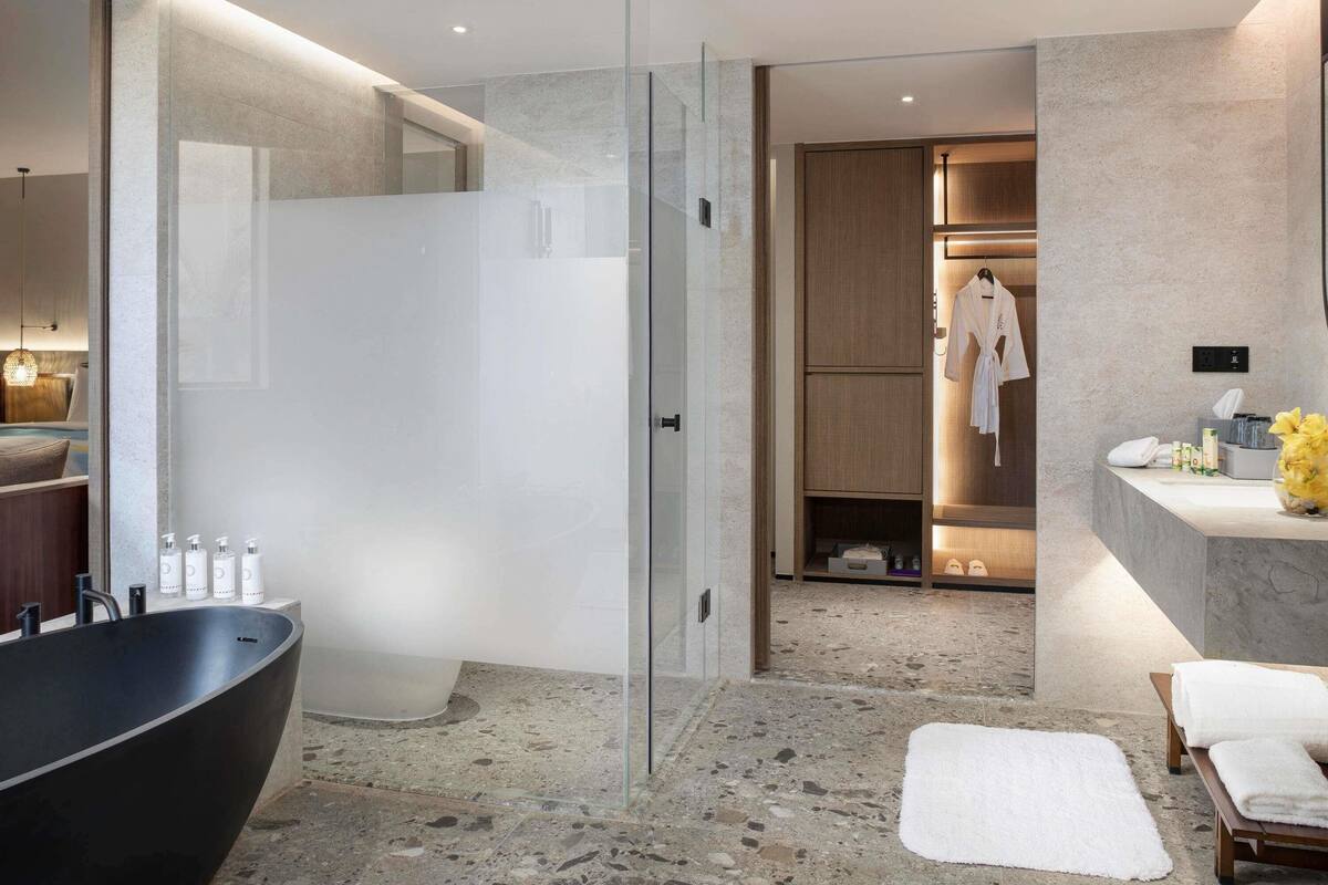 A modern bathroom with a freestanding bathtub, a glass shower enclosure, and a vanity with toiletries.