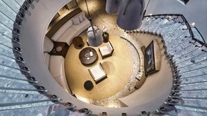 Un espace intérieur circulaire comprenant un coin salon central, une petite table et des luminaires suspendus.