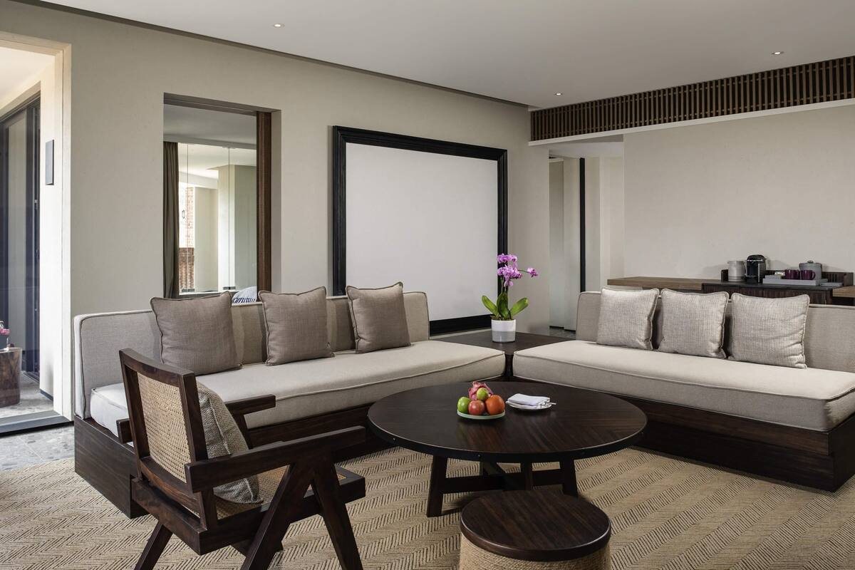 A modern living room with a sectional sofa, a round coffee table, and a small side table with a potted orchid.