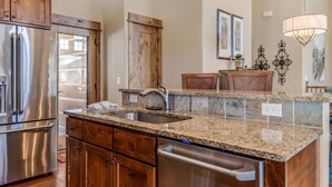 A kitchen with granite countertops, stainless steel appliances, wooden cabinets, and a built-in dishwasher.