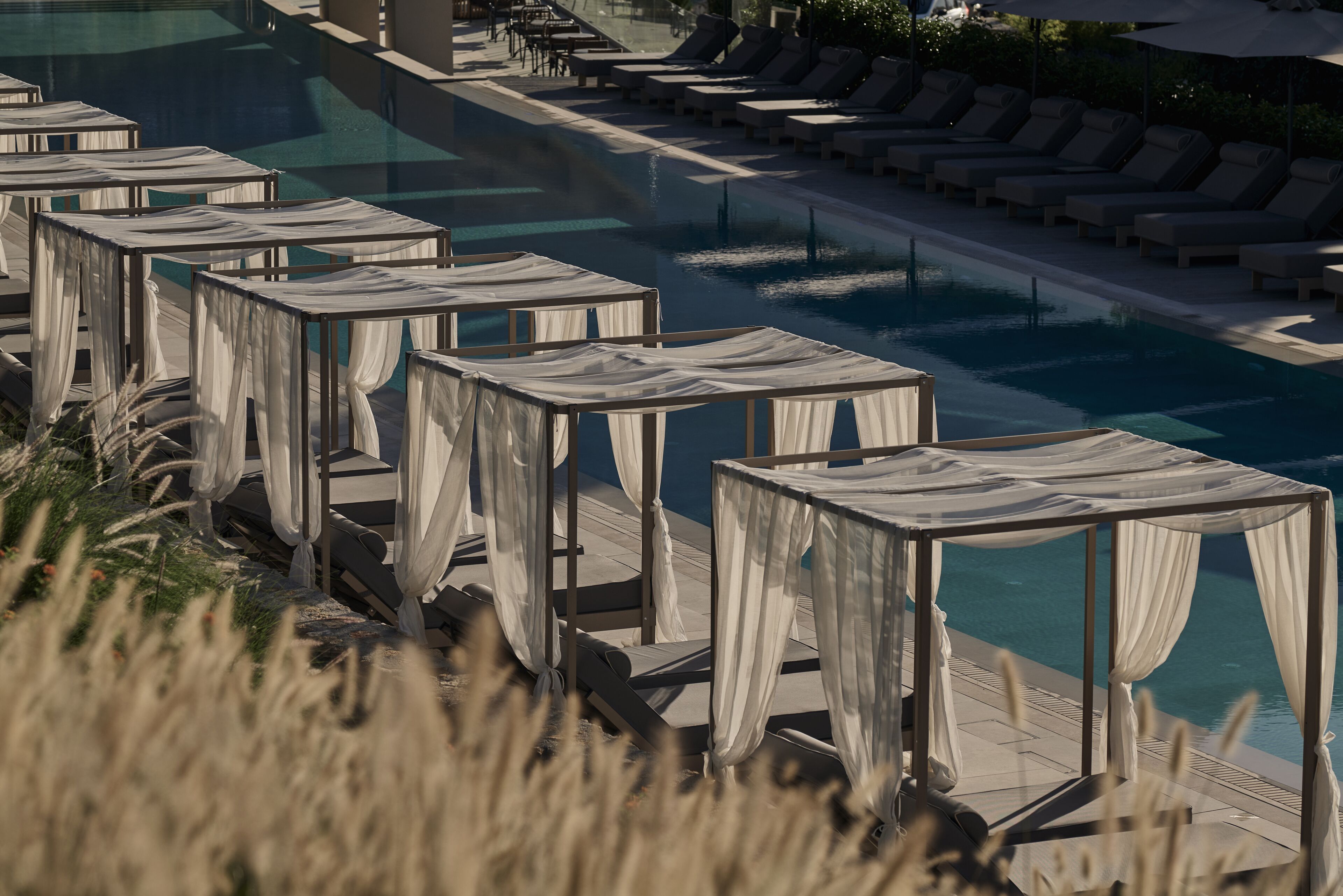 Area piscina con diverse sdraio e zone relax all'ombra.