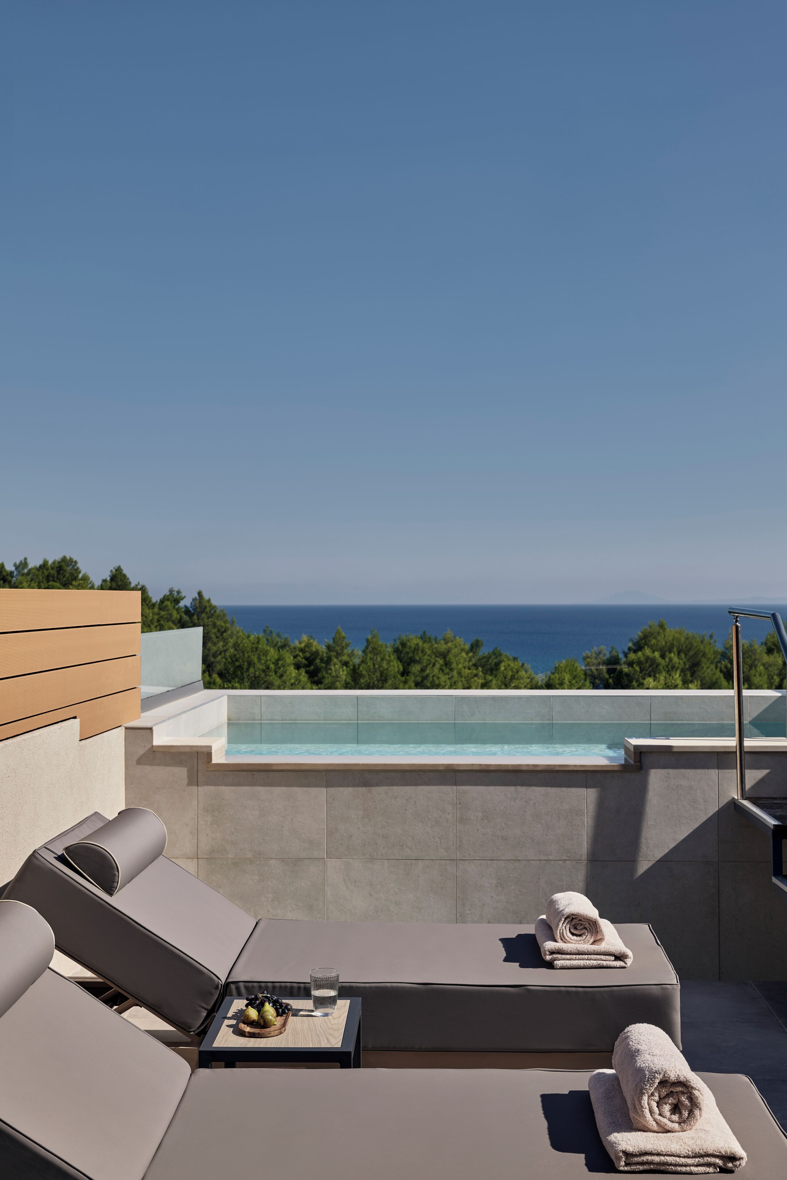 Une terrasse sur le toit avec une piscine, des chaises longues et une vue sur l’océan.