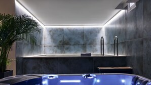 Uma área de spa moderna com uma banheira de hidromassagem, um porta-toalhas e uma planta em vaso.