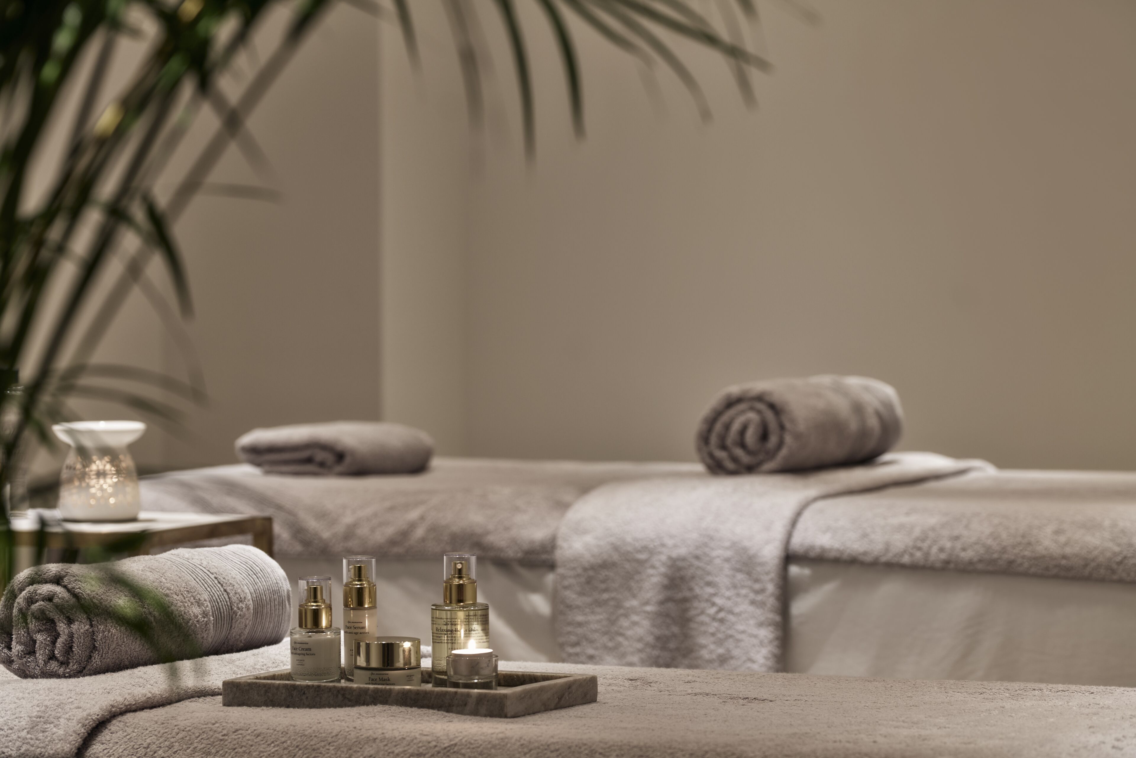 A spa area with towels, candles, and skincare products on a massage table.