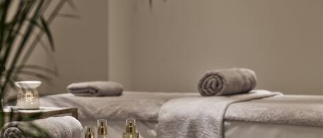 A spa area with towels, candles, and skincare products on a massage table.