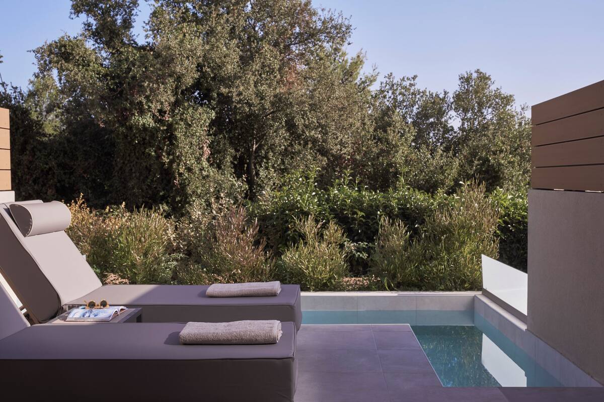 A modern outdoor pool area with two lounge chairs, a book, and towels.