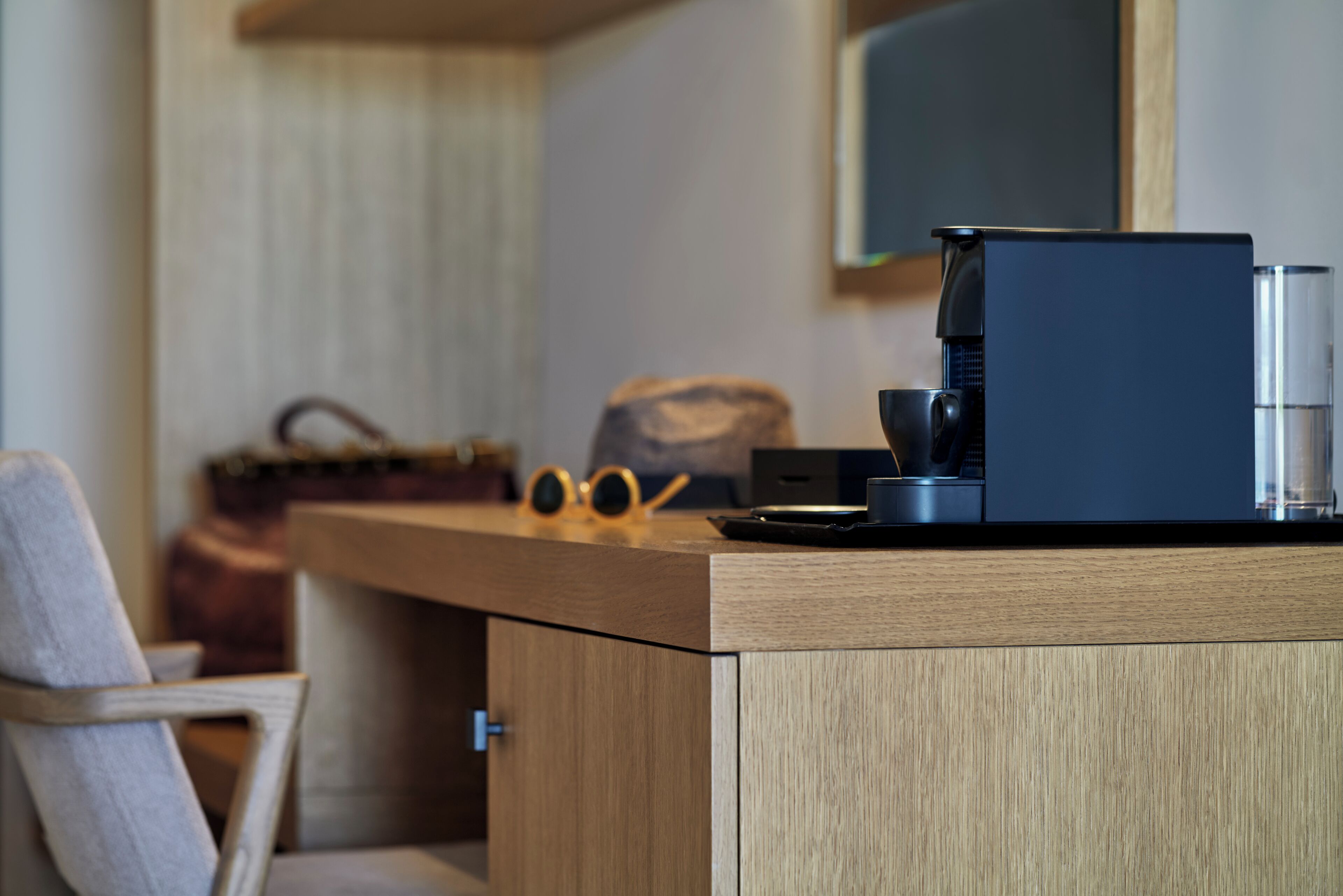 A modern kitchen with a coffee machine, a bag, and a pair of sunglasses on the counter.