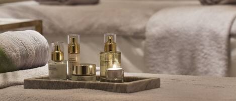 A spa setting with a massage table, towels, and skincare products.