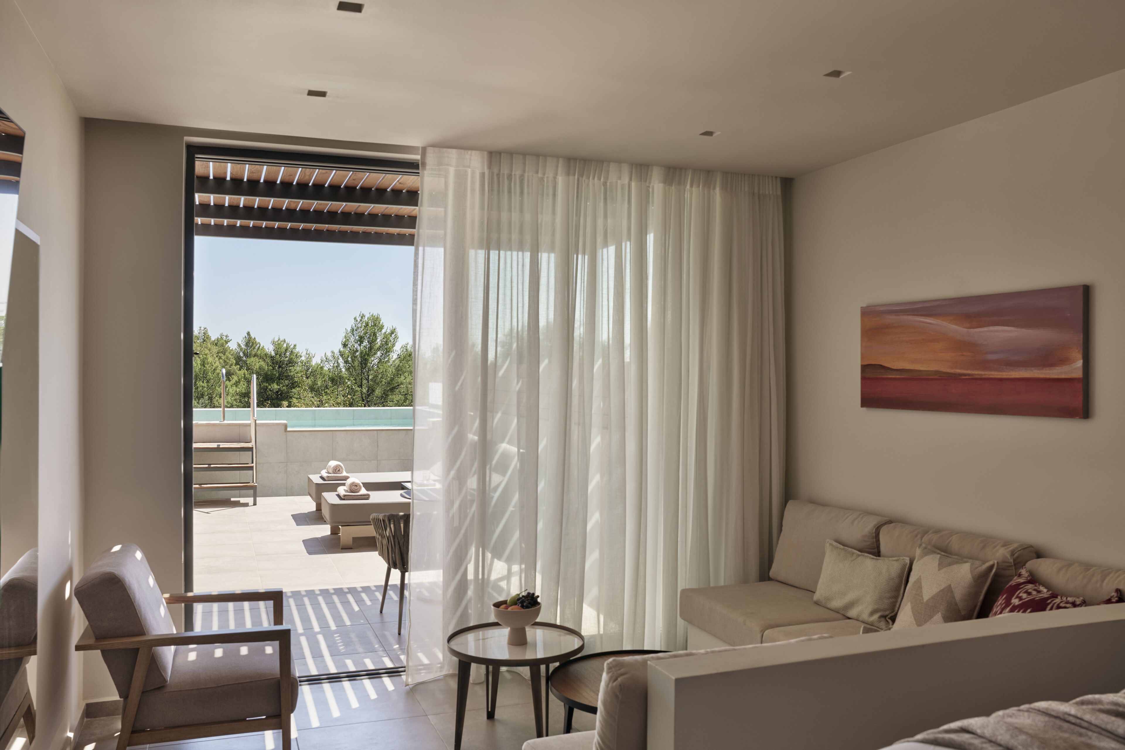 Een moderne woonkamer met een bank, fauteuils, een salontafel en een balkon met tuinmeubilair.