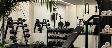 A gym with weightlifting equipment, a bench, and a mirror.