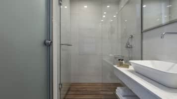 Ein modernes Badezimmer mit Duschkabine aus Glas, einem weißen Waschbecken und Holzboden.