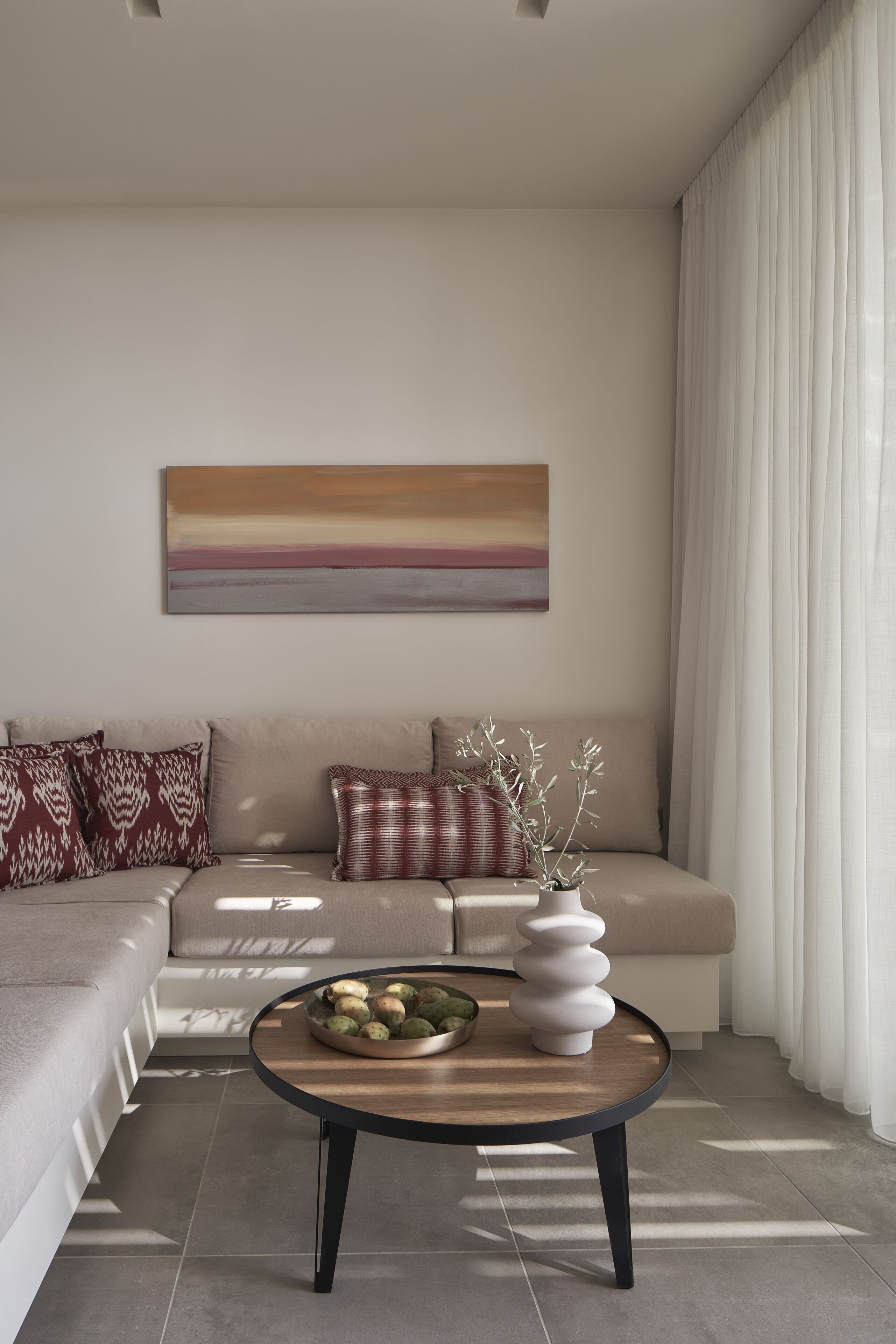 Una sala de estar moderna con un sofá, una mesa de centro con adornos y un cuadro en la pared.