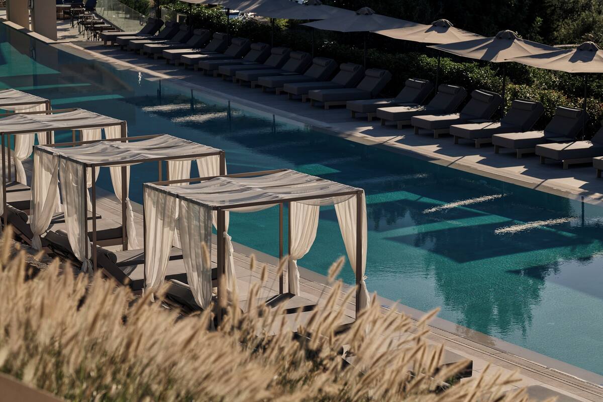 A pool area with lounge chairs and small tables, surrounded by greenery.