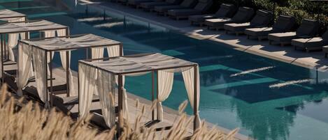 A pool area with lounge chairs and small tables, surrounded by greenery.