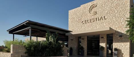 A hotel entrance with a stone facade and a covered patio area.