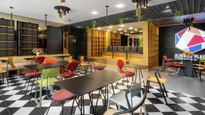A modern lounge area with black and white checkered flooring, multiple seating options including sofas and chairs, and a large bookshelf. - ibis Bucharest Politehnica (Bucharest)