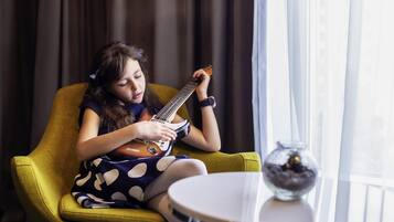 Una persona sentada en un sillón amarillo tocando una guitarra.