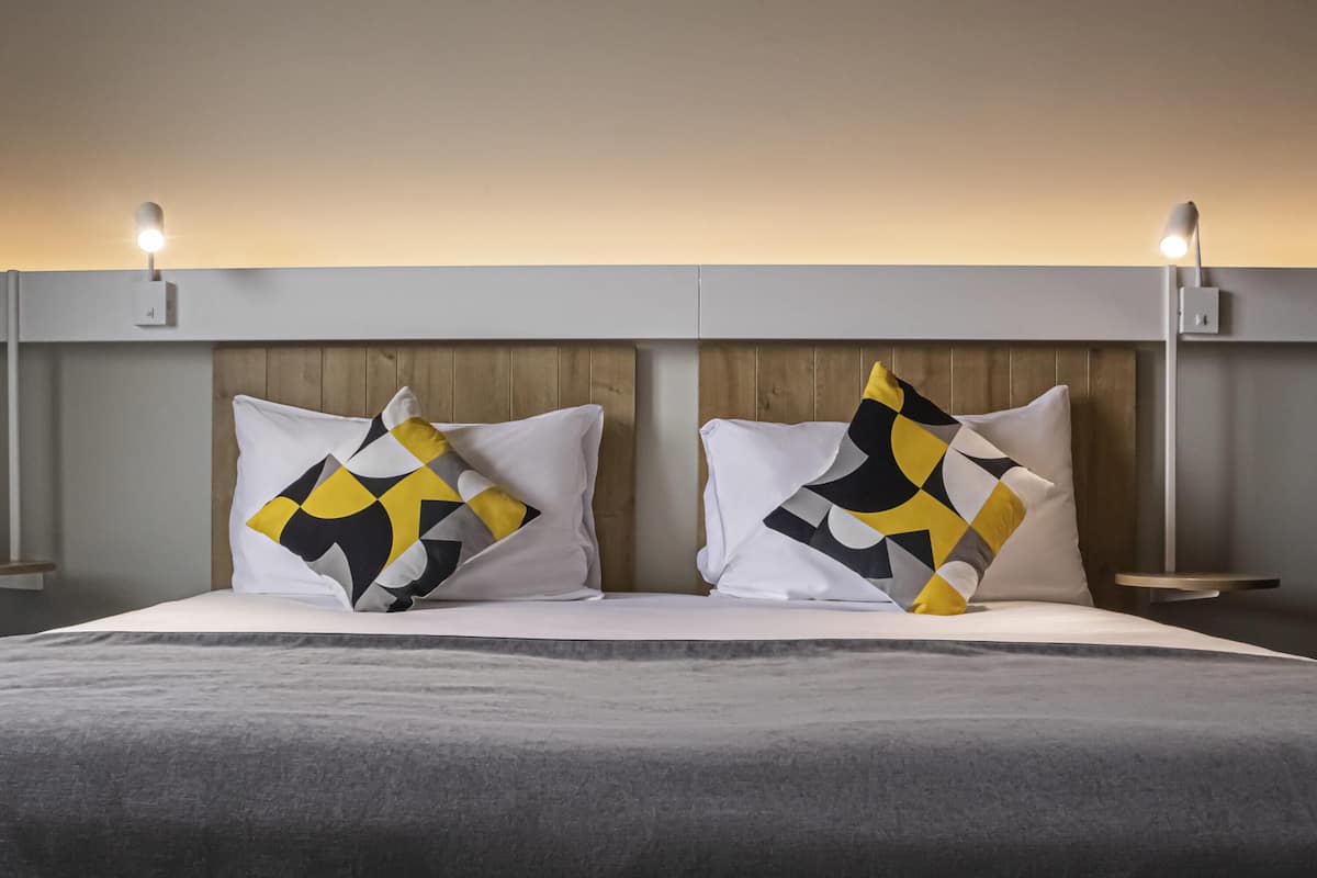 A bed with two pillows, a wooden headboard, and bedside lamps.