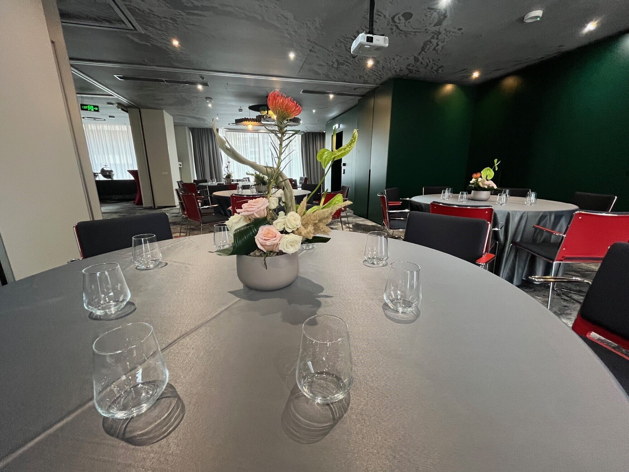 A conference room with a round table, chairs, and a floral centerpiece.