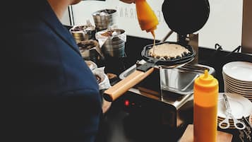 Une personne qui cuisine sur un gaufrier et a une bouteille de sauce à portée de main.