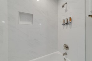 Bathtub, hair dryer, towels, shampoo