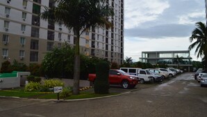 A parking lot with multiple cars, a red vehicle, and a building with balconies. - Dencio's Crib (Lapu-Lapu City)