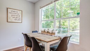 A dining area with a wooden table, four chairs, and a window with a view of trees. - Fort Worth Hideaway Near Downtown (Fort Worth)