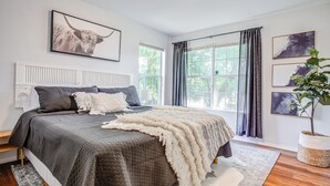 A bedroom with a large bed, a window with curtains, a radiator, and a framed picture on the wall. - Fort Worth Hideaway Near Downtown (Fort Worth)