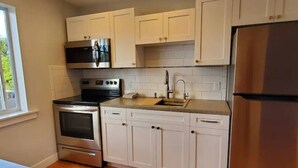 A kitchen with white cabinets, stainless steel appliances, and a window. - Central, Quiet and Beautifully Decorated #1 (Fort Lauderdale)