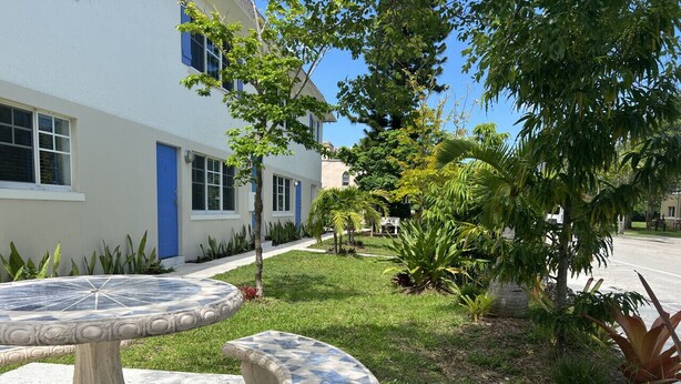 A courtyard with a stone table and bench, surrounded by greenery and a building with a blue door. - Central, Quiet and Beautifully Decorated #1 (Fort Lauderdale)